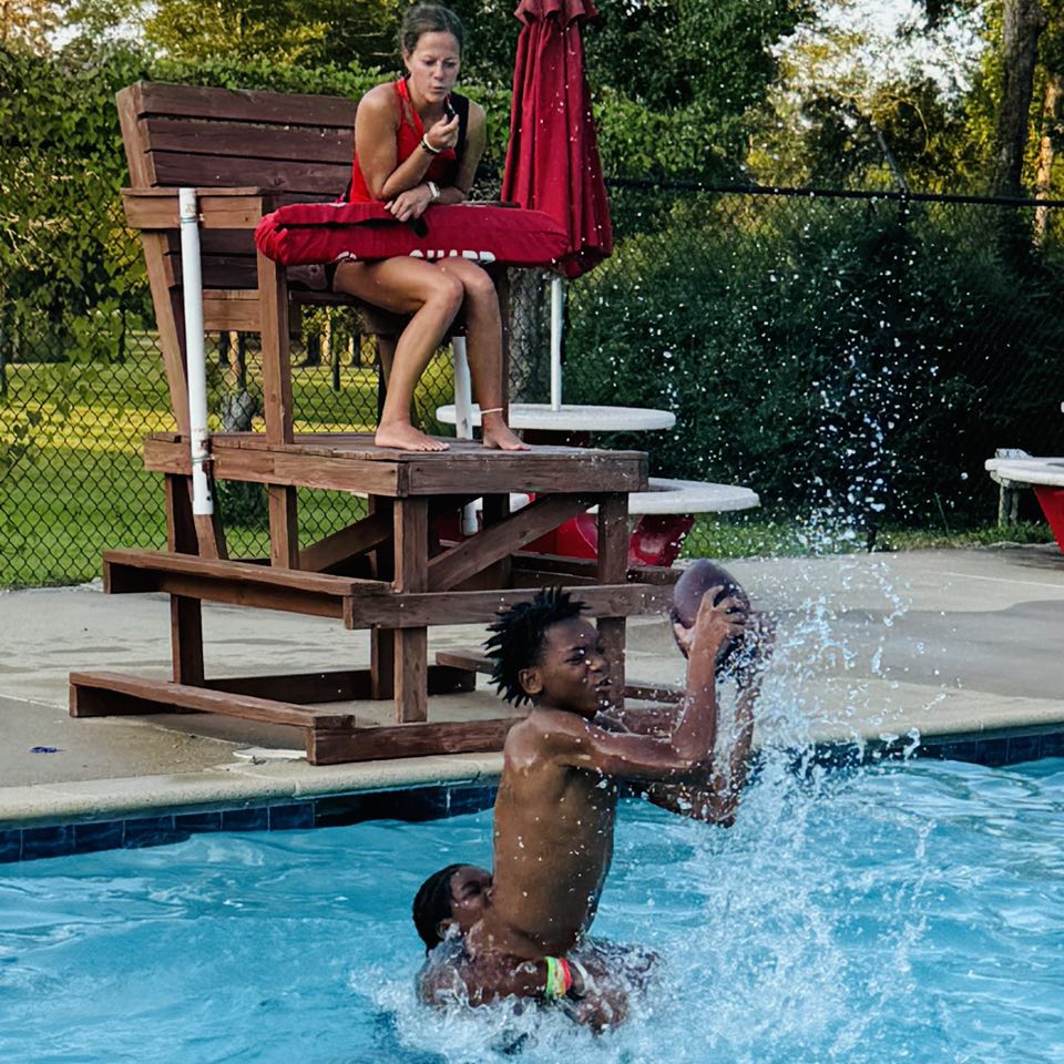 A boy in a pool catching a football.